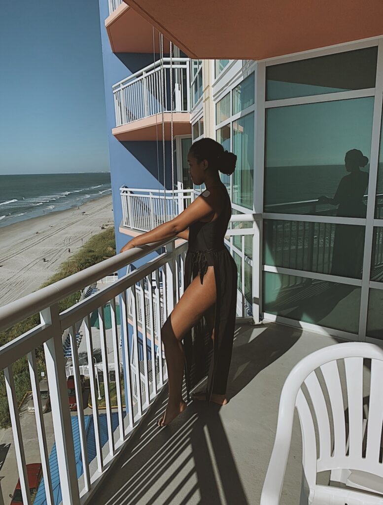 Woman standing on a hotel balcony overlooking Myrtle Beach on a couples vacation