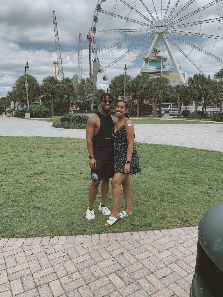 Married Couple posing in front of the SkyWheel at Myrtle Beach, capturing a joyful moment during their romantic beach vacation
