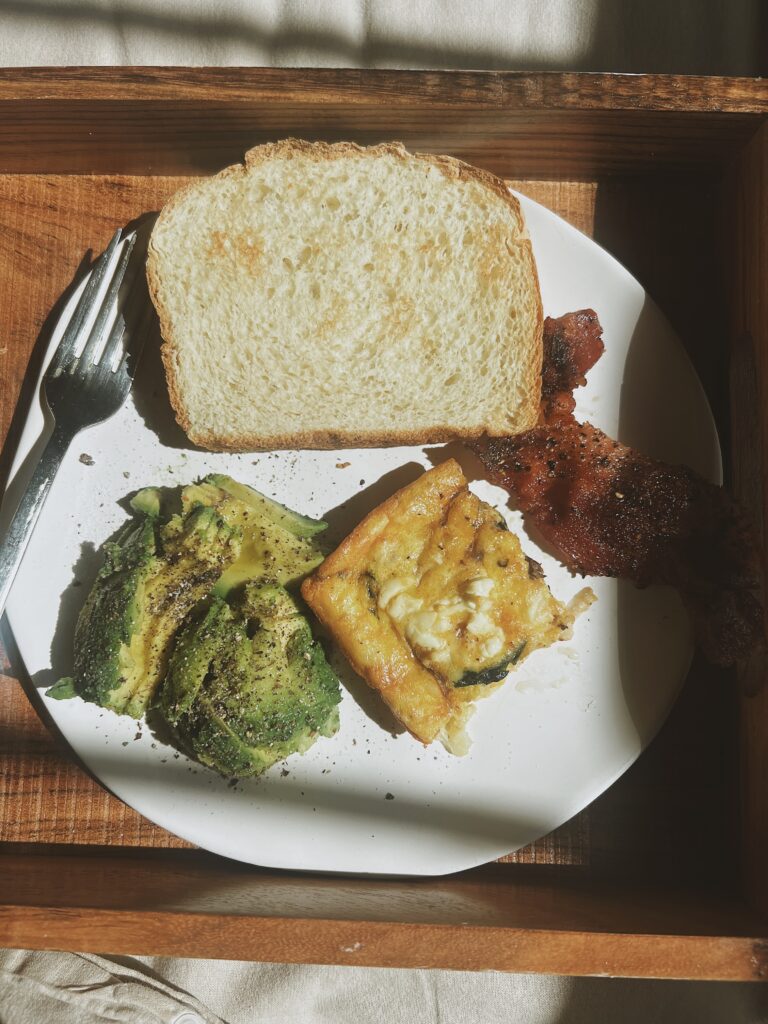 Spinach and Feta Frittata on a white place with bread, bacon and avocado