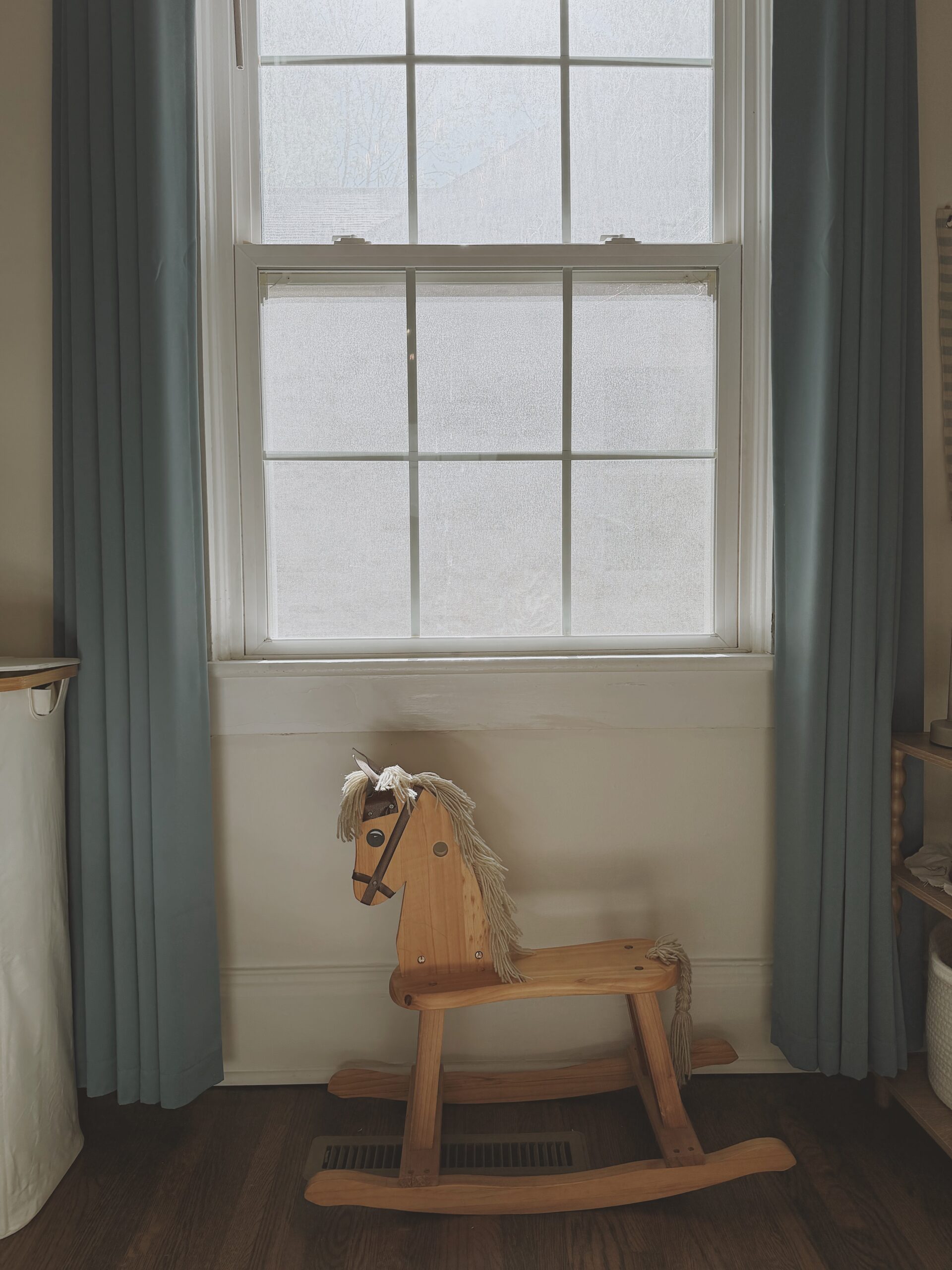 Rocking horse in front of window with blue curtains