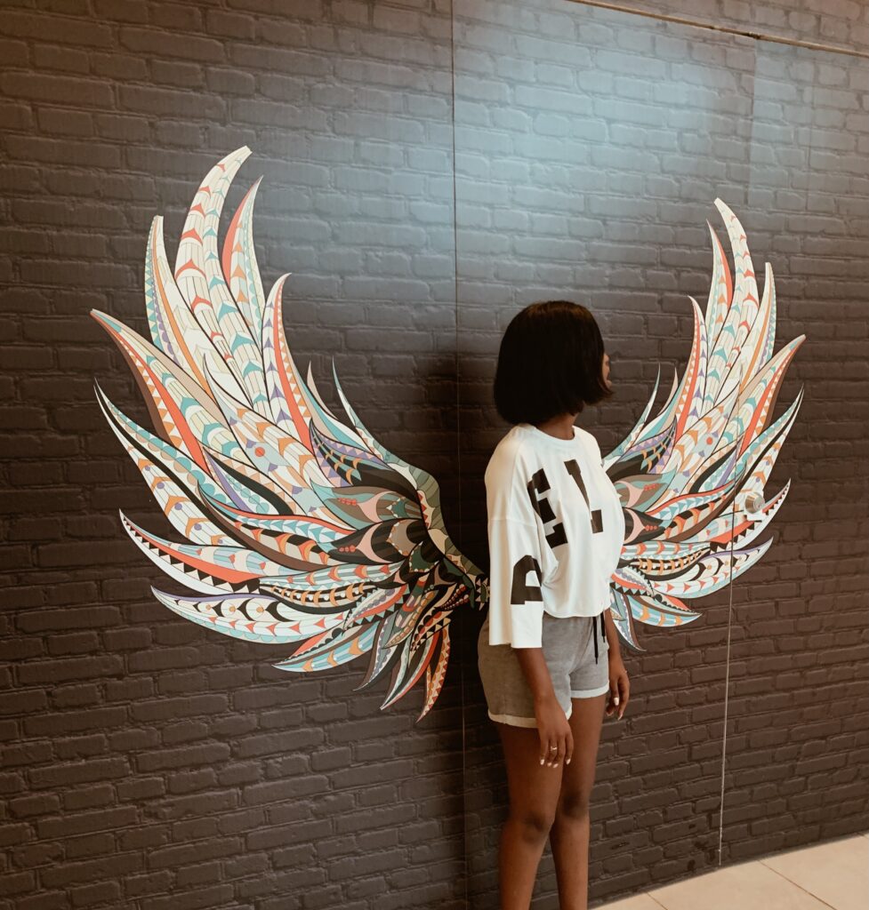 Woman standing at a wall art with angel wings