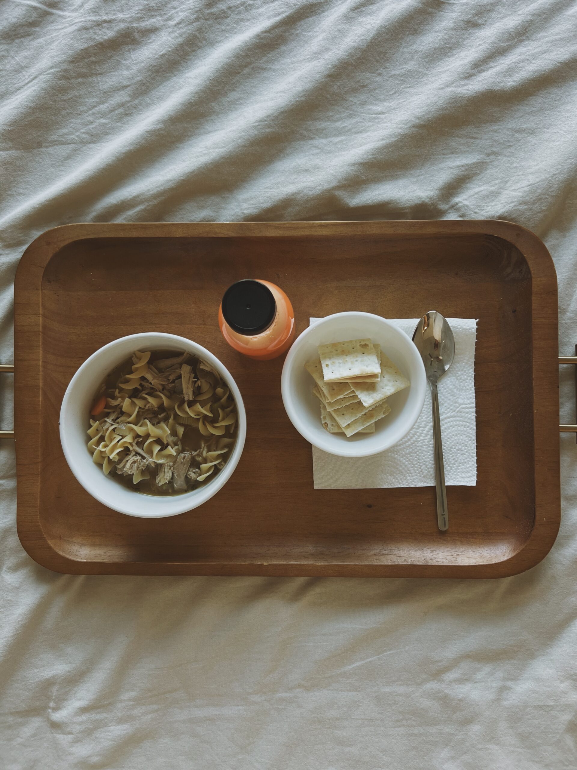 Classic chicken noodle soup with egg noodles served in a bowl on a tray