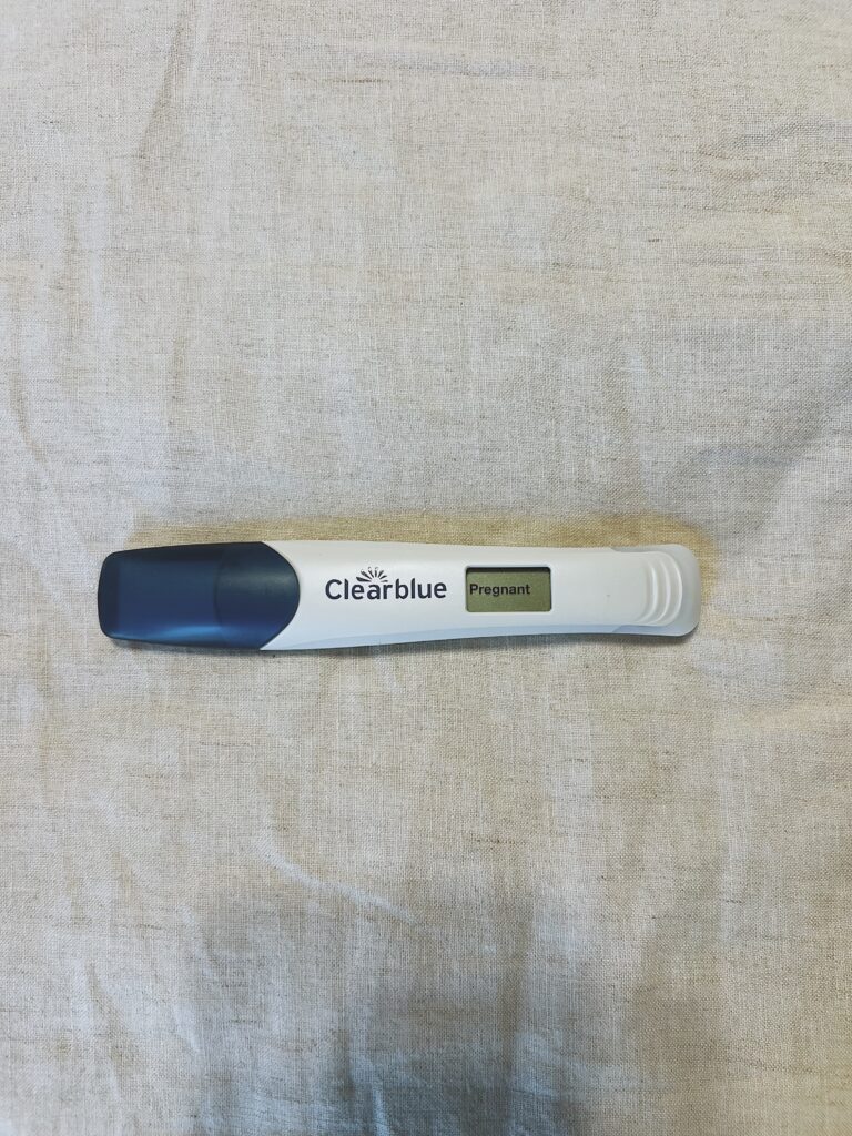A positive Clearblue pregnancy test on the bed