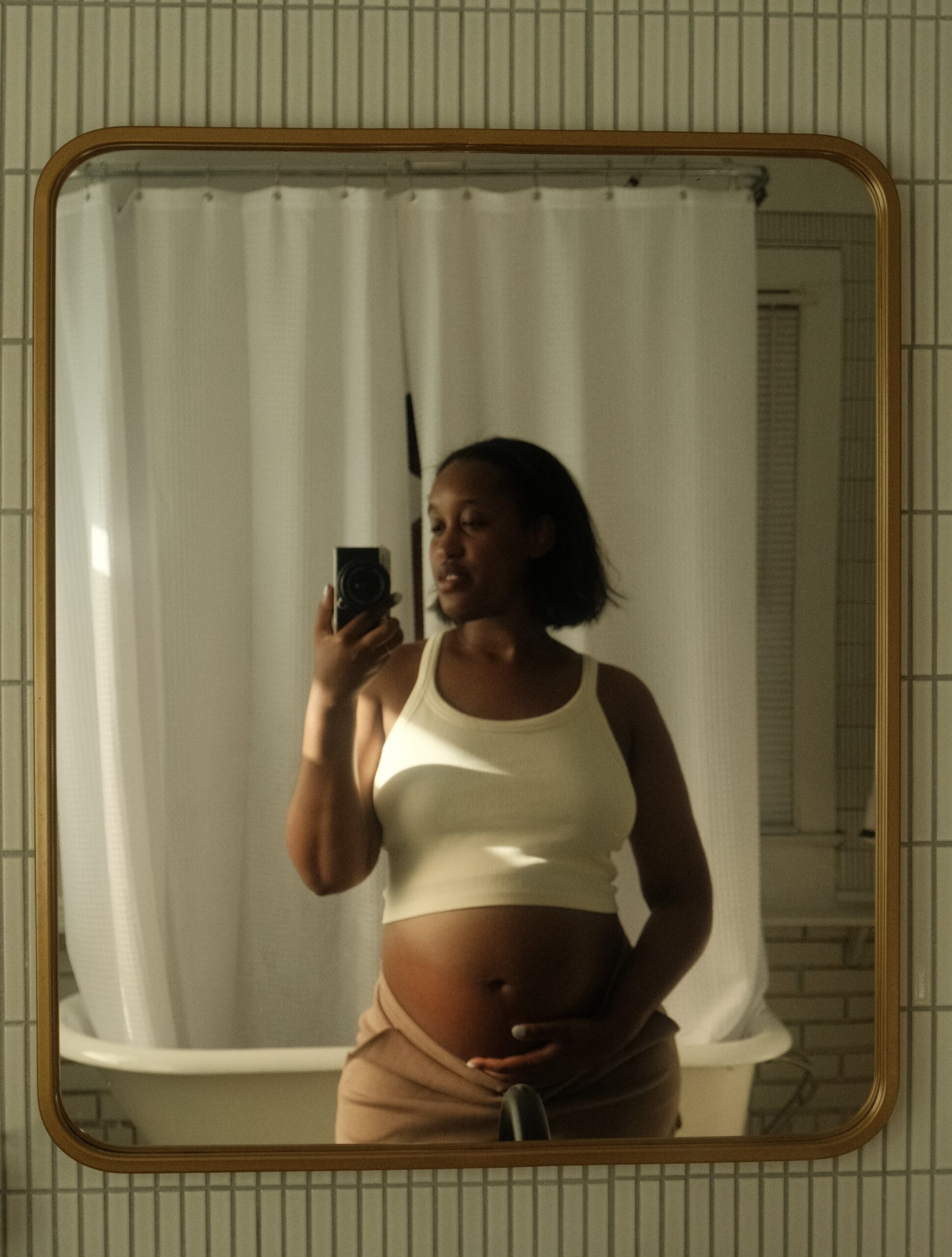 Pregnant woman in front of a mirror taking a picture with a camera